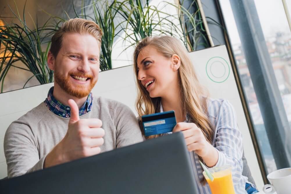 Smiling couple with credit card making online purchase