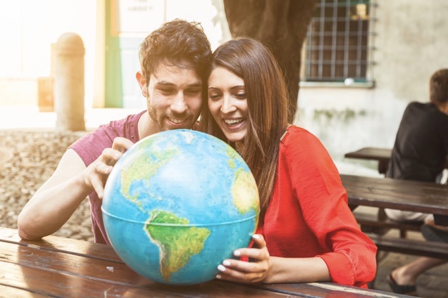 Which Country Has The Most Millionaires Couple looking at a globe
