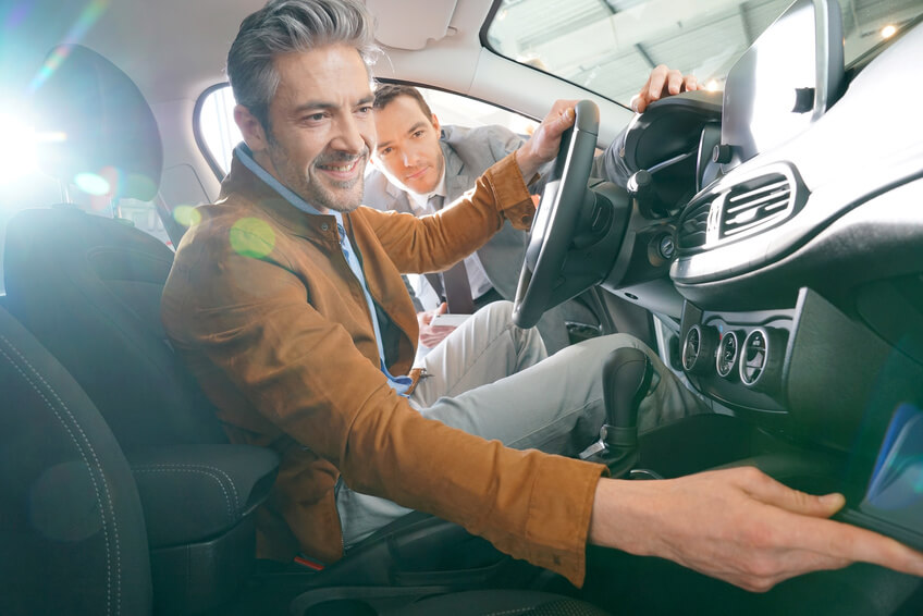 If Your Life Was $100 Grey-haired man sitting inside vehicle in car dealership