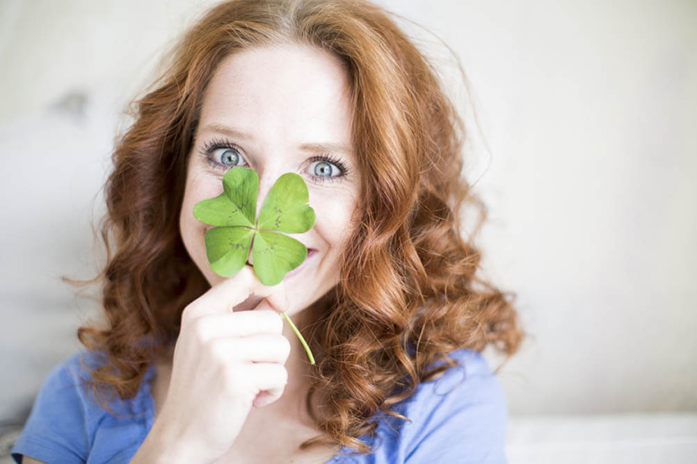 Woman holding large shamrock in front of her face