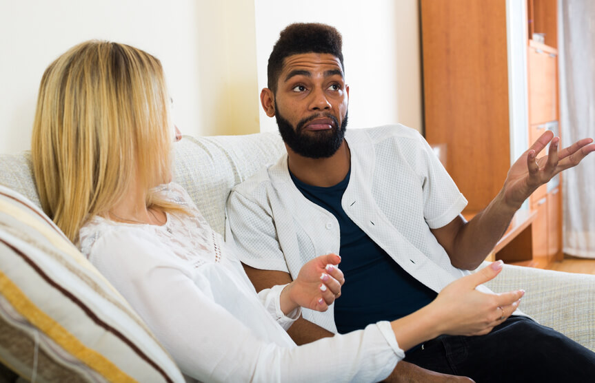 Man and woman seated on sofa in conversation