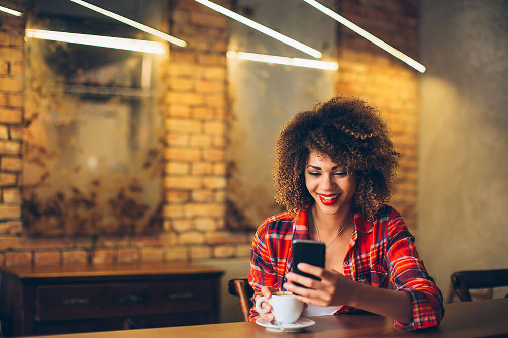 Happy woman checking her phone in a cafe