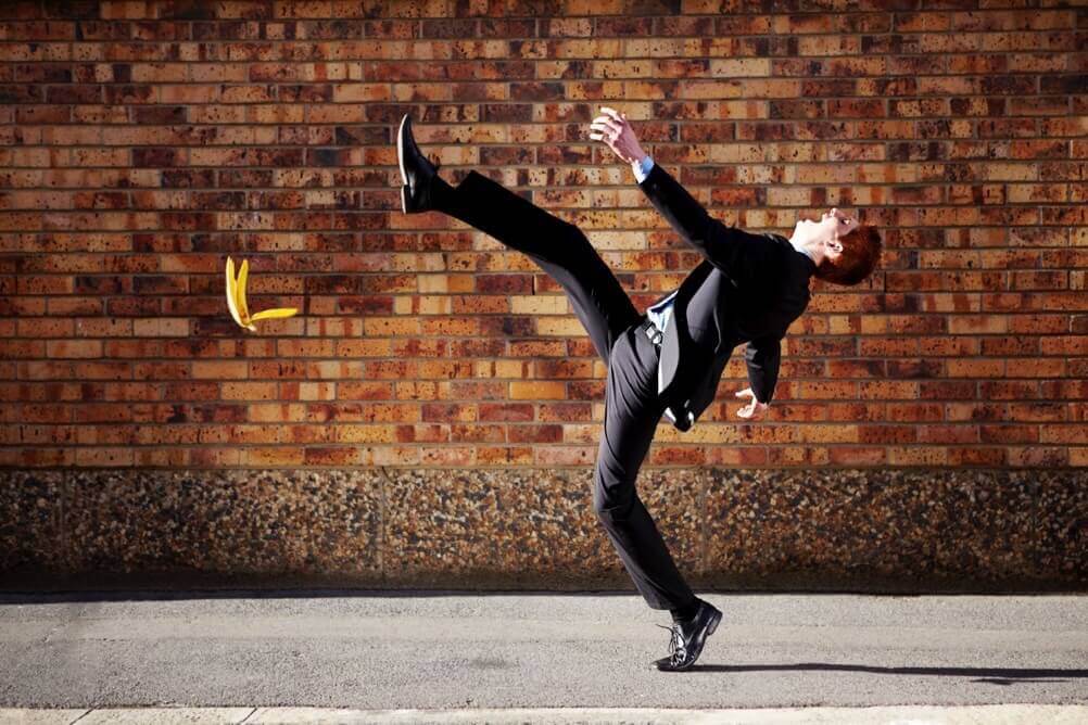 Why is Friday the 13th unlucky? Man in a suit slipping on a banana skin in front of a brick wall