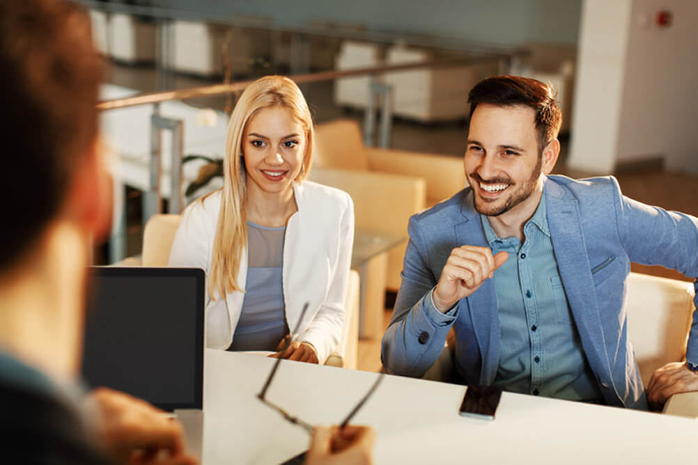 Ten Tips for what to do when you win the lottery jackpot Couple seated at desk, smiling and speaking with a financial advisor