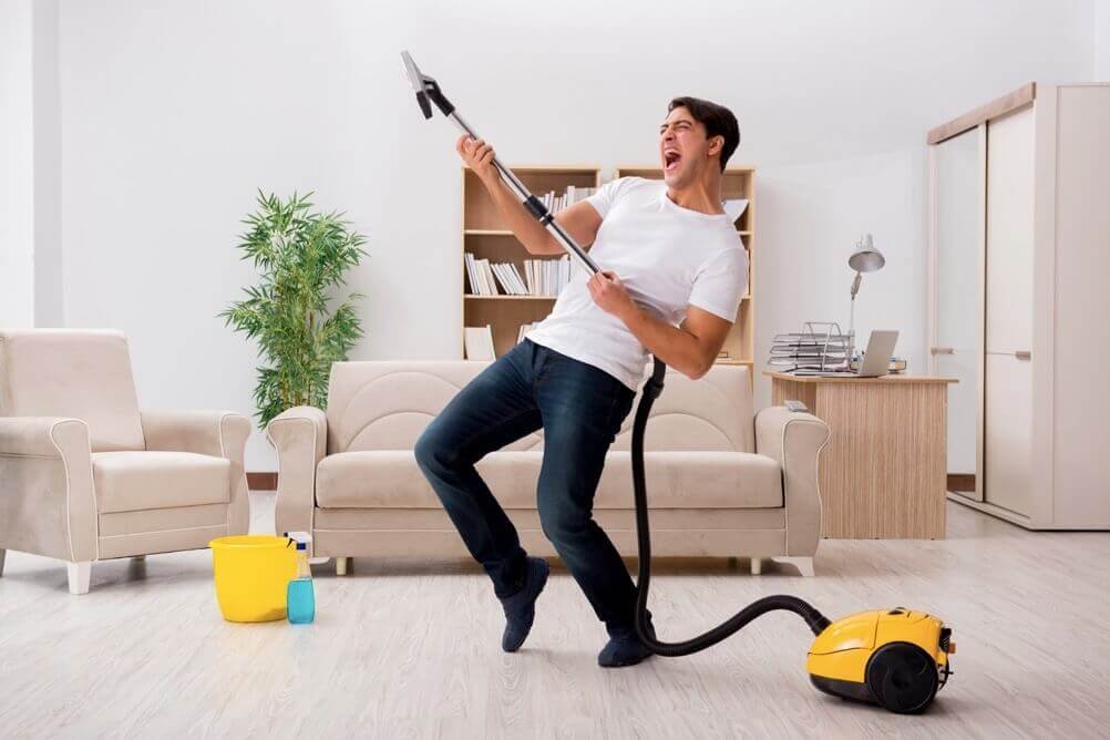 KonMari Method of Cleaning Man dancing with vacuum cleaner in front roon