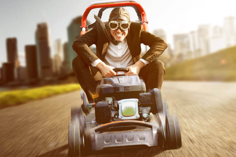 Man in a suit driving a lawnmower at record breaking speed
