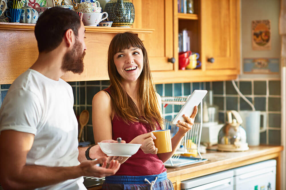 Couple play the Irish Lotto on their tablet over breakfast in their kitchen