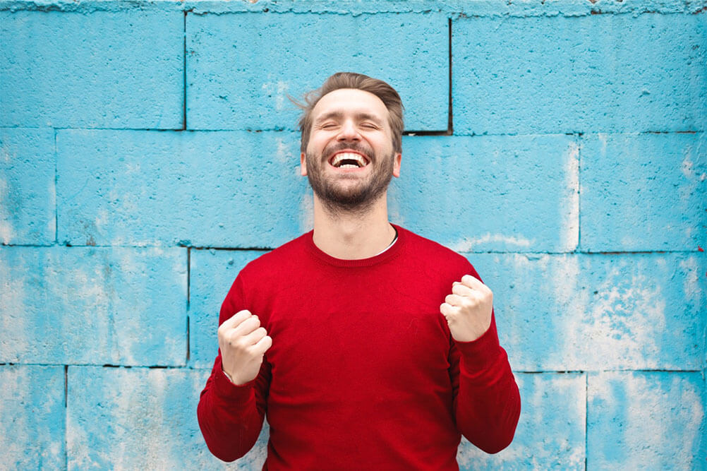 Man wearing red sweater celebrates