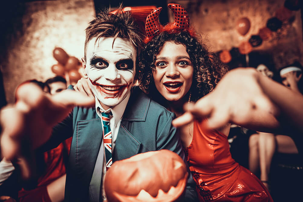 The origins of Halloween traditions Couple in costume at Halloween holding a carved pumpkin