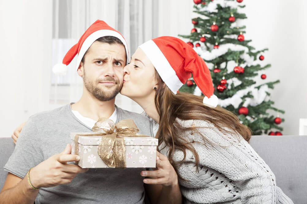 Boyfriend looks unhappy with gift from his girlfriend as she kisses him