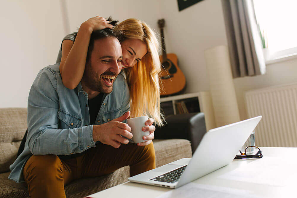 A couple celebrate as they look at the results of the lottery on their laptop