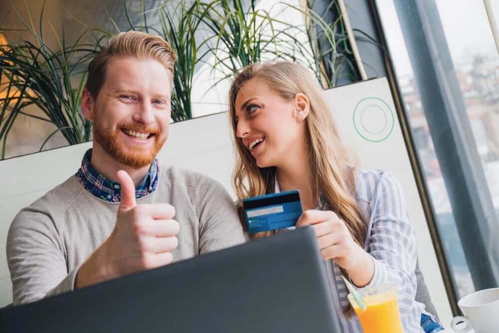 You're in safe hands when you gamble online with Lottoland Smiling couple with credit card making online purchase