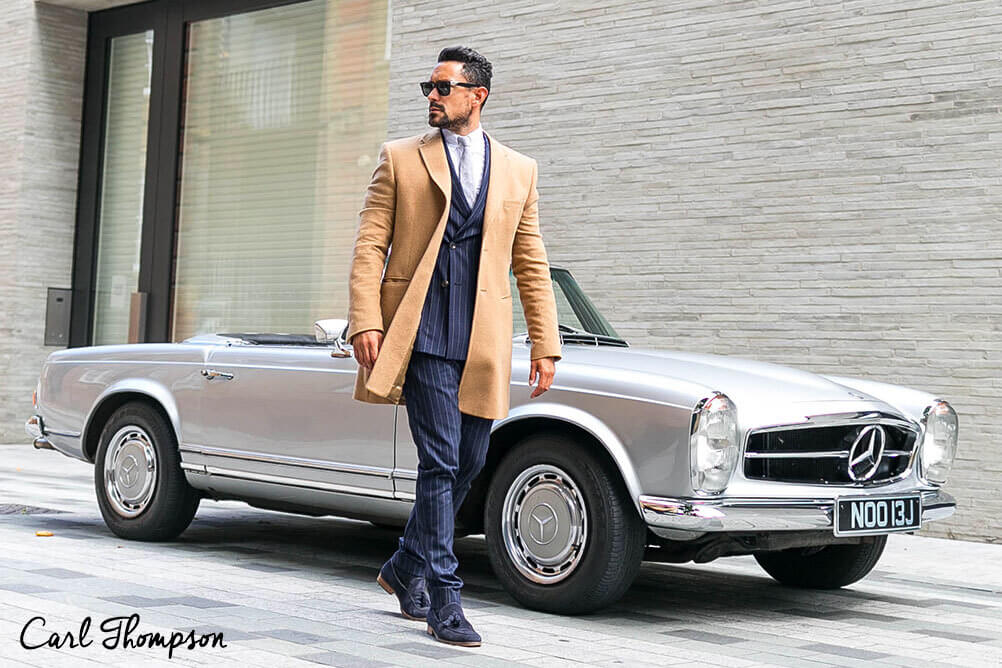 Carl Thompson dresses like a rich man standing in front of an expensive car