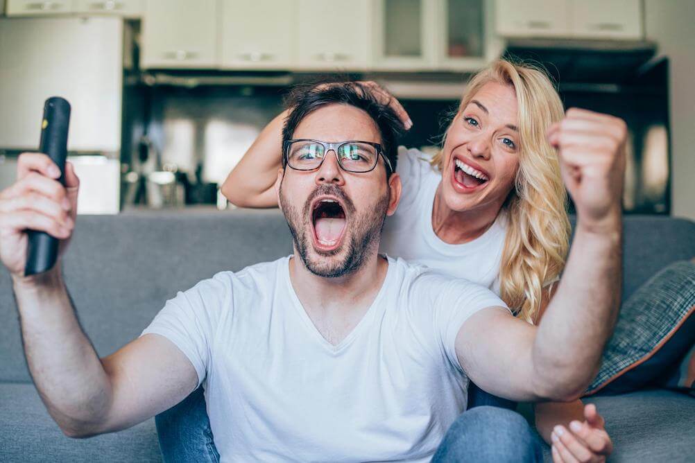 Happy-couple-looking-at-phone-playing-lottery