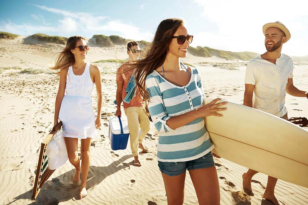 Friends at the beach with a surfboard wondering if they are more likely to win the lottery or be eaten by a shark