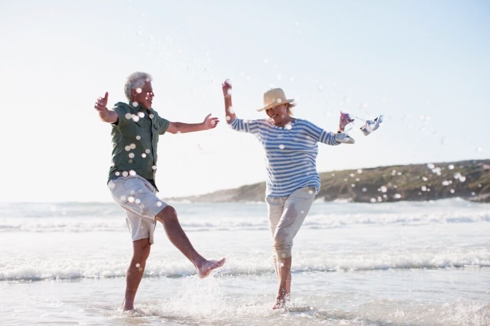 Senior couple celebrating their second lottery win on the beach