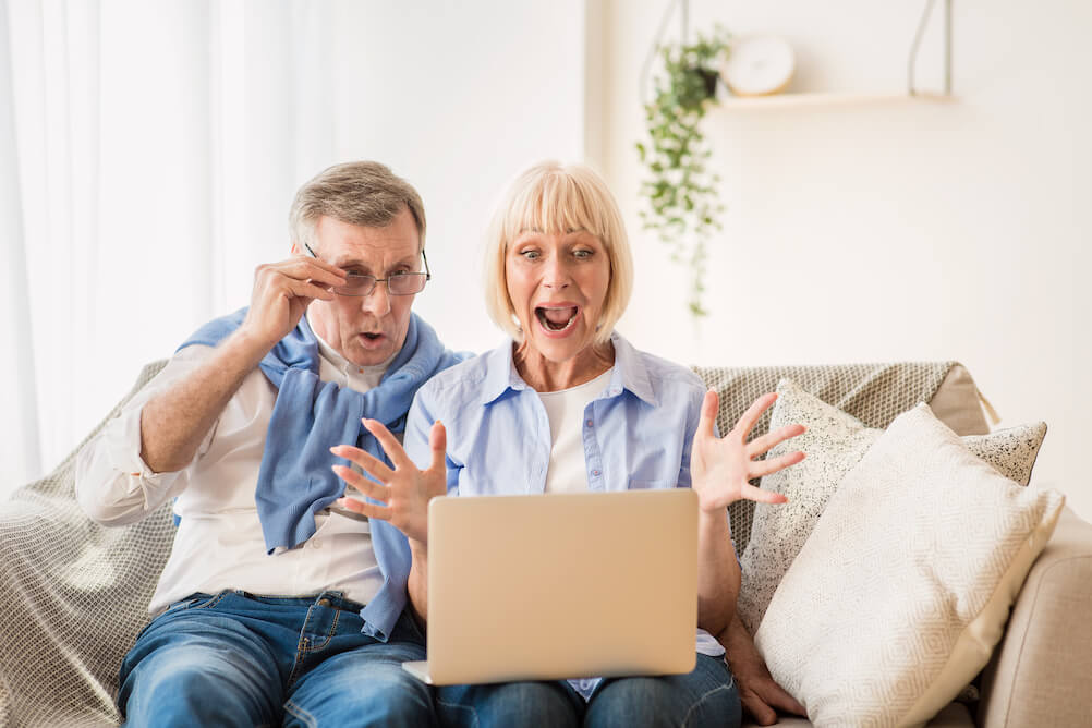 How much is the lottery? Surprised elder couple checking lottery ticket prices on their laptop