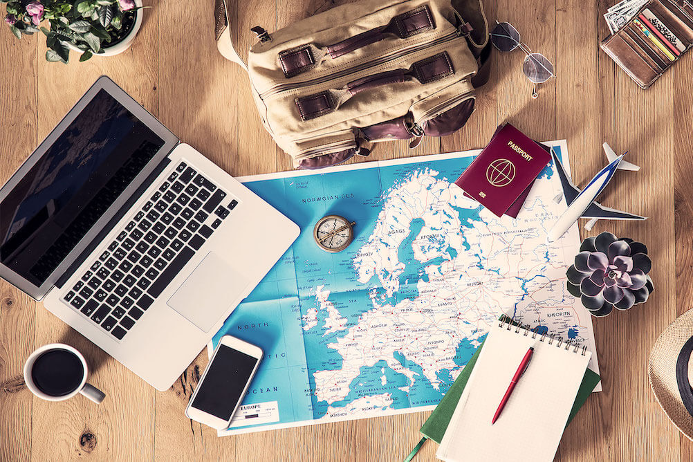 A photograph of a laptop and the world map laid out on a table to book event tickets