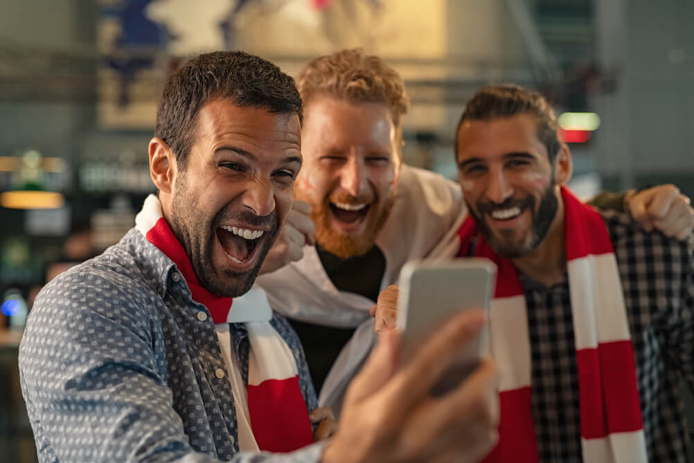 How to bet on Sports with Lottoland three guys with sports scarves betting on sports with lottoland online on their mobile