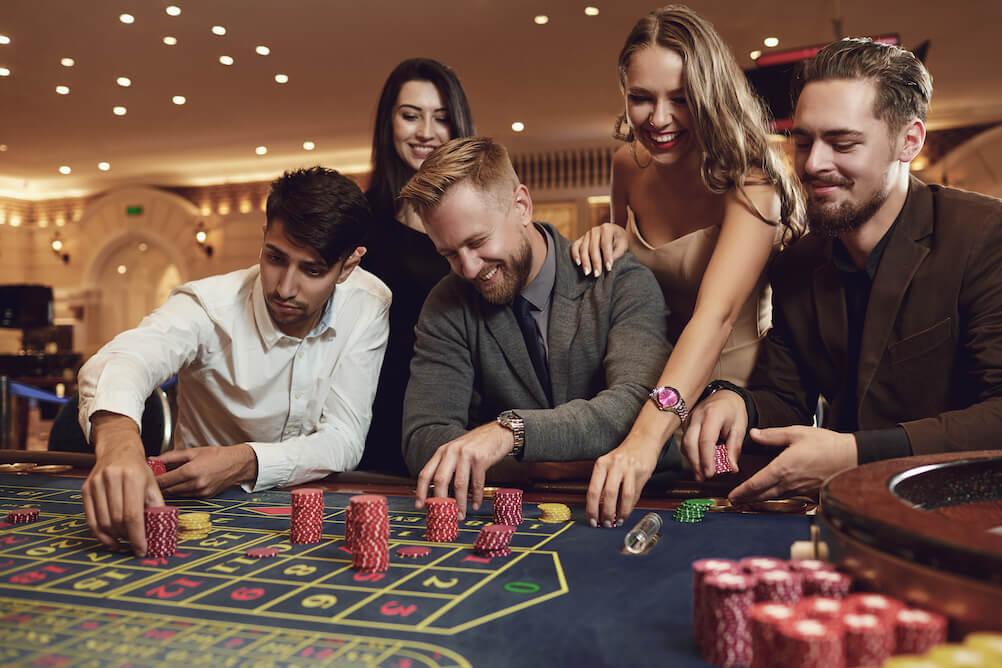 Three men and two women playing roulette. They checked the casino games odds before playing