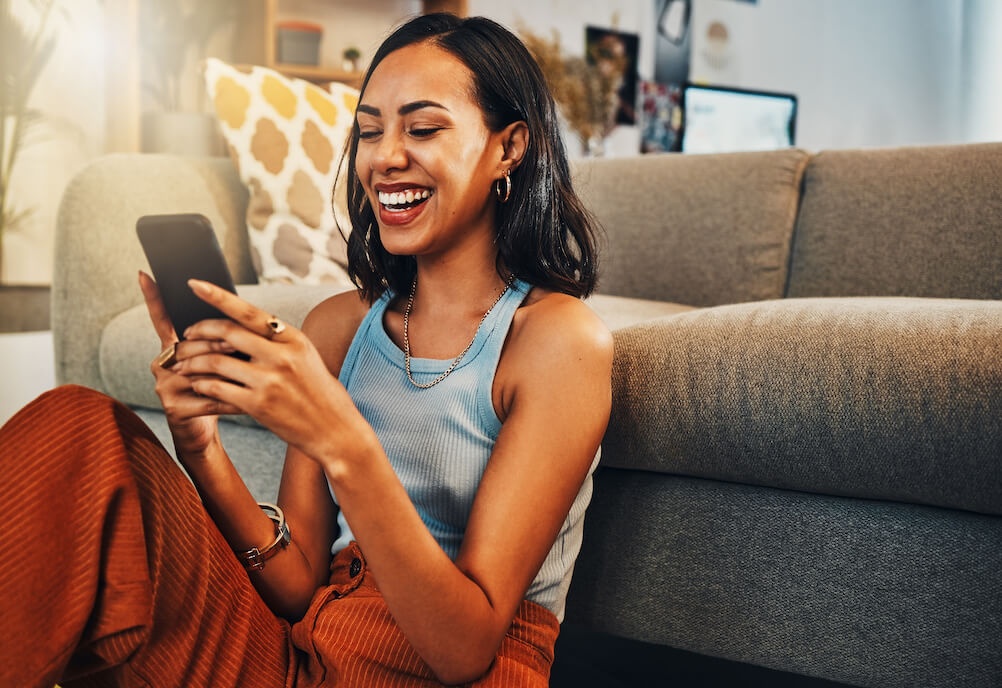 A woman on her phone, happy reading stories about who won the lotto