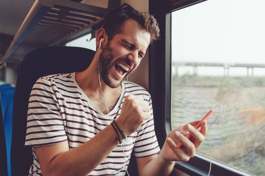 A man travelling by train and enjoying playing the best Yggdrasil slots on his mobile phone