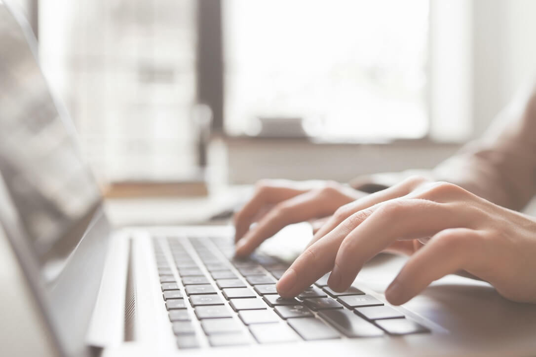 A close up of fingers typing on a laptop keyboard, coding the latest AI in gambling trend.